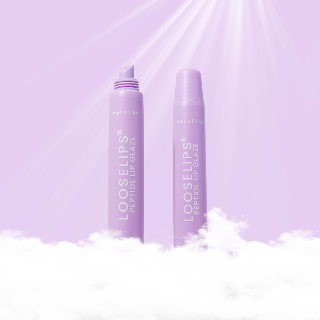 Two lavender lip glaze tubes rom Looselips stand on white clouds against a light purple background with soft sun rays shining through.