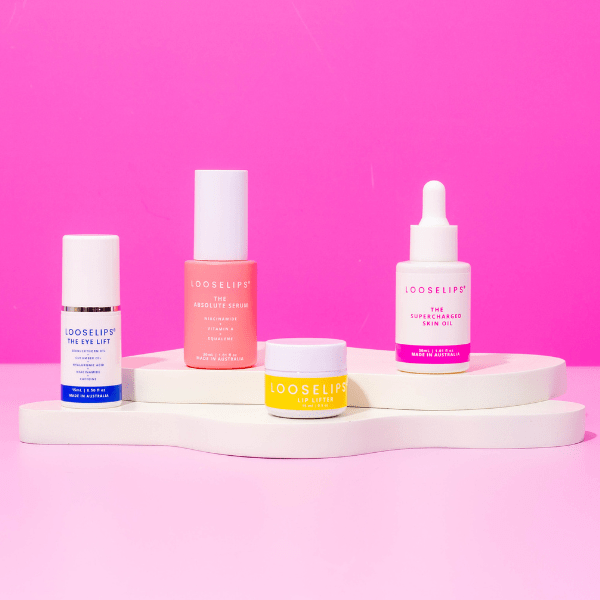 photo of the looselips anti-aging self-care skin care set consisting of the eye lift, absolute serum, looselips lip lifter and the supercharge skin oil against a bright pink background.